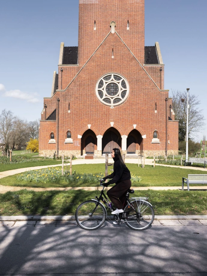 groen kerkplein met fietser als passant