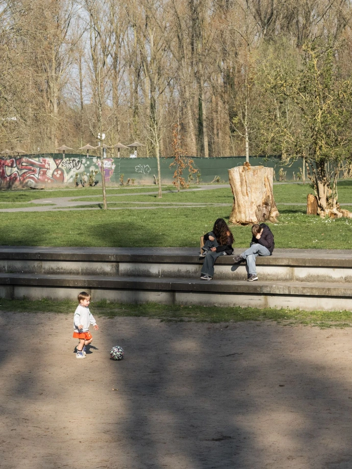 Spelend kindje en hangende jongeren in een park